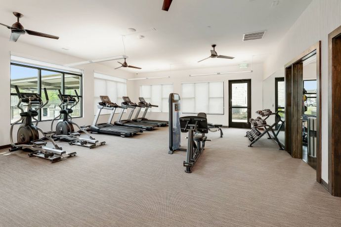 The Narrows Modern gym with treadmills, exercise bikes, and weight machines in a bright room with large windows.