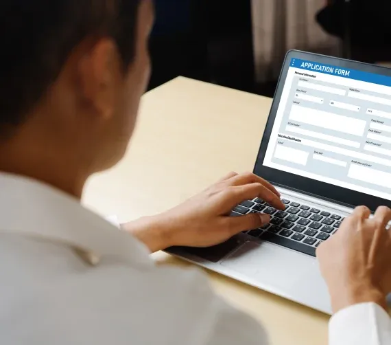 The Narrows Person filling out an online application form on a laptop at a desk.