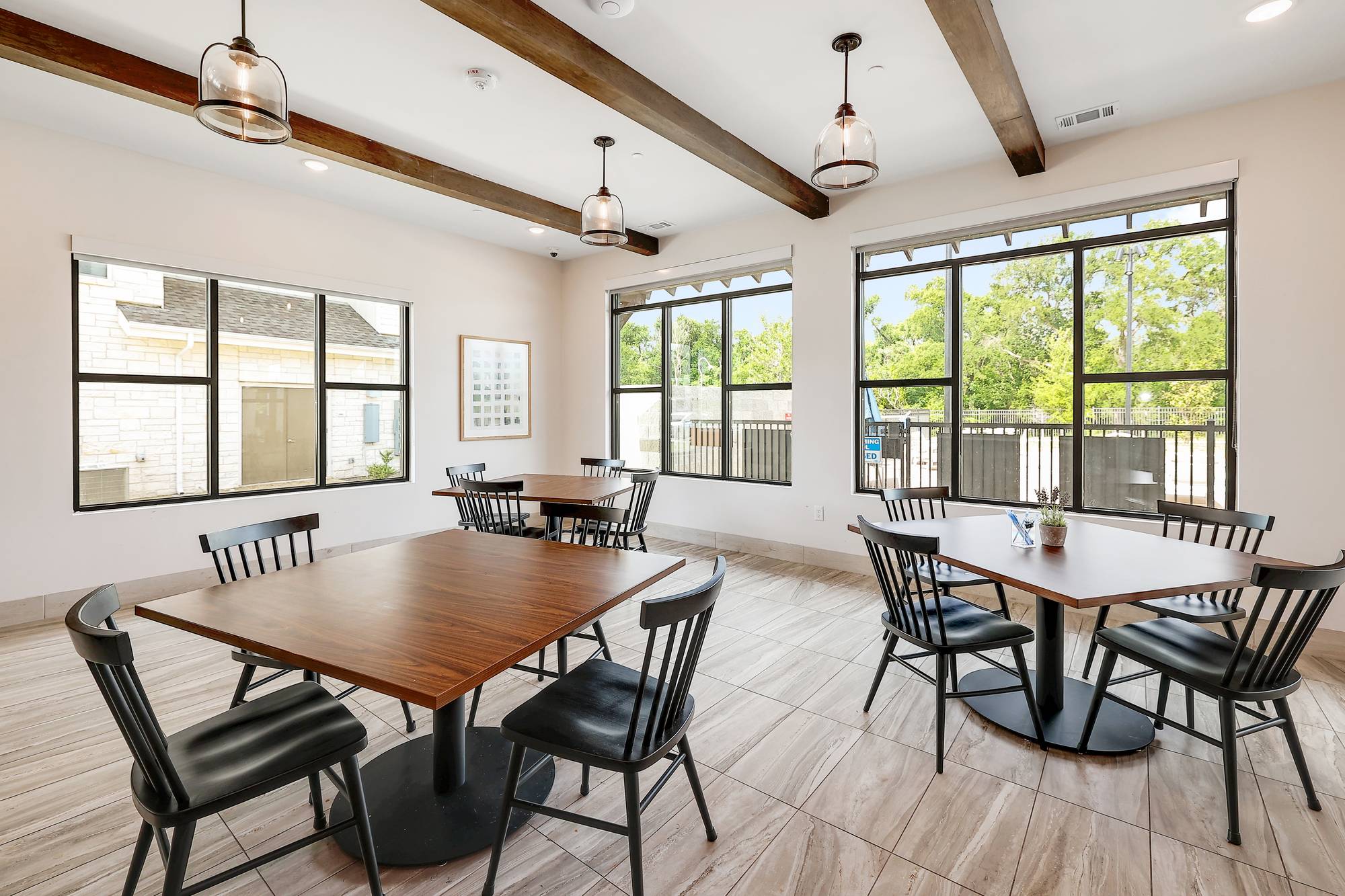 The Narrows Modern dining area with wooden tables, black chairs, large windows, and three pendant lights.